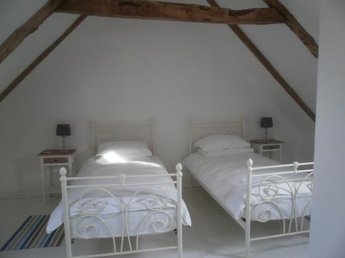 two beds in a room with white walls at Gites du Manoir in Runan
