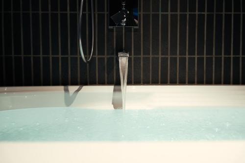 a bath tub with water coming out of a faucet at Alternest Kamakura in Kamakura