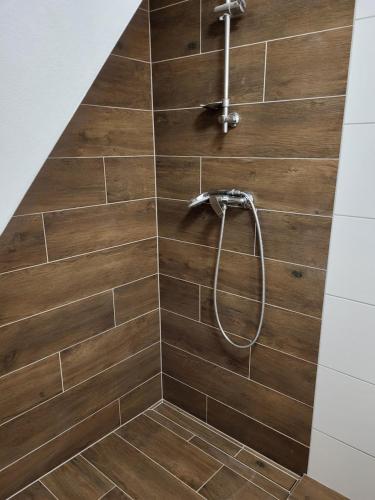 a bathroom with a shower with a wooden wall at Domek U hřiště in Hlinsko