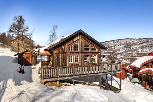 a wooden house with a deck in the snow at Blåstöten Osthang - Ramundberget in Bruksvallarna