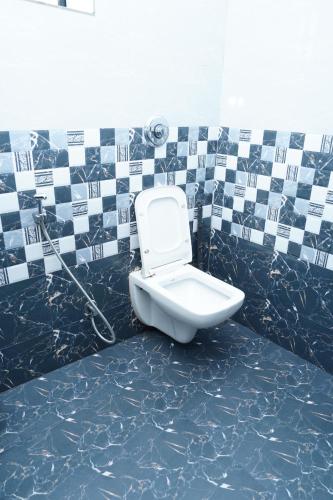 a bathroom with a toilet in a tiled wall at Sukruthi service apartment 3BHK in Mangalore