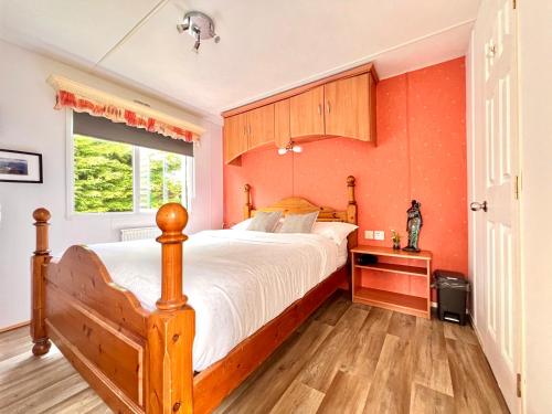 a bedroom with a wooden bed and a window at Hawthorn Self Catering Cottages in Benderloch