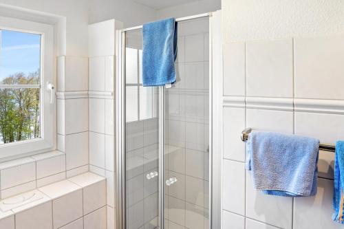 a bathroom with a shower with blue towels at Bungalow am Haussee in Himmelpfort