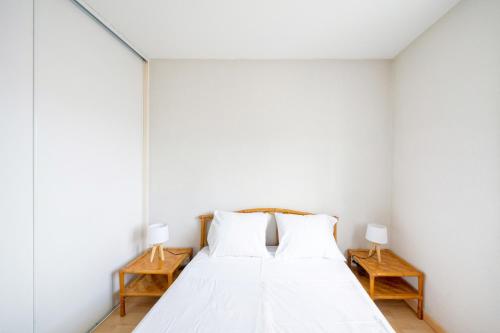 a white bedroom with a bed with two night stands at Plein soleil, Capbreton in Capbreton