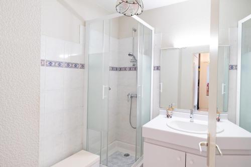 a white bathroom with a shower and a sink at Plein soleil, Capbreton in Capbreton