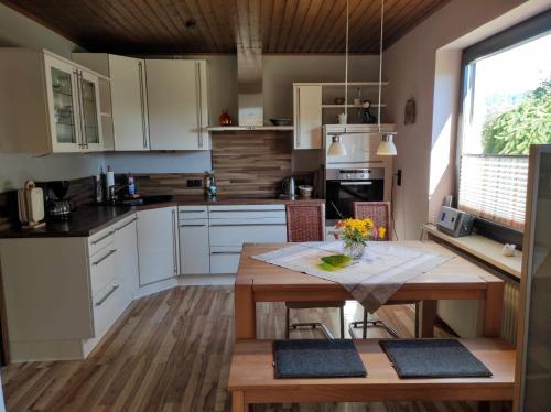a kitchen with white cabinets and a wooden table at Ferienwohnung Klaus in Ebermannstadt