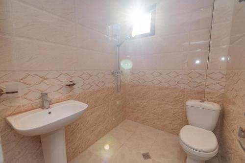 a white bathroom with a sink and a toilet at Hotel Chateau Ochia in Koromkhet'i