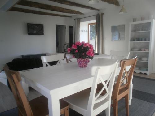 a white dining room table with a vase of flowers on it at Gites du Manoir in Runan