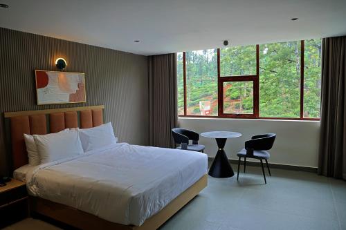 a bedroom with a bed and a table and windows at Better Suites Hotel in Meppādi
