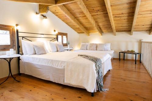 a bedroom with two beds with white sheets and wooden ceilings at Anerada Houses - Seaviews Above Egremni in Lefkada in Athani