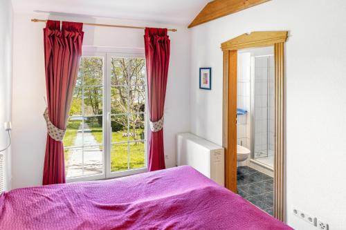 a bedroom with a purple bed and a window at Bungalow am Haussee in Himmelpfort