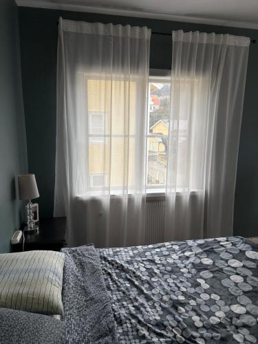 a bedroom with a bed and a window with white curtains at Two rooms and kitchen in central Uddevalla in Uddevalla