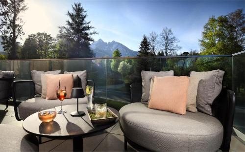 a balcony with two chairs and a table with wine glasses at Hotel Lomnica in Tatranská Lomnica