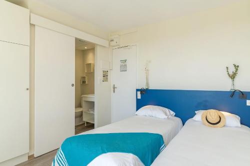 two beds in a room with a blue wall at Résidences LES HAUTES PLAINES in Gréoux-les-Bains