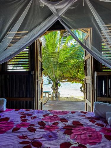 a bed in a room with a view of the ocean at Tsara Beach in Nosy Be