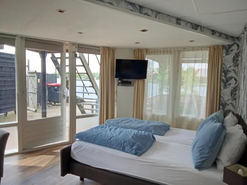 a bedroom with a bed with blue pillows and a television at B&B aan het water in Earnewâld