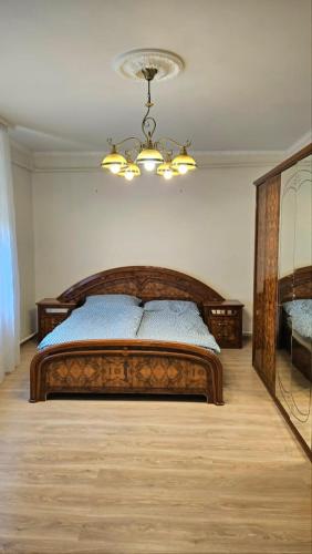 a bedroom with a wooden bed and a chandelier at Balatoni HUNOR Vendégház in Balatonvilágos