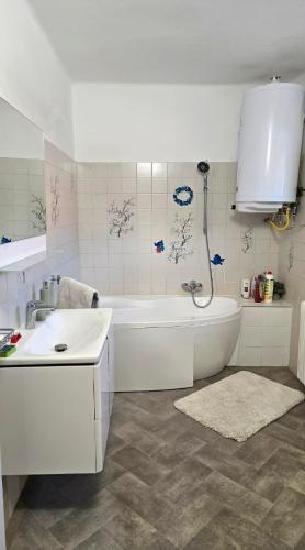 a white bathroom with a tub and a sink at Balatoni HUNOR Vendégház in Balatonvilágos