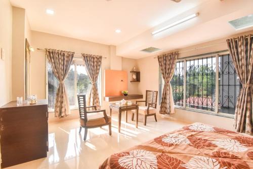a bedroom with a bed and a desk and chairs at Klassone Bunglow in Khandāla