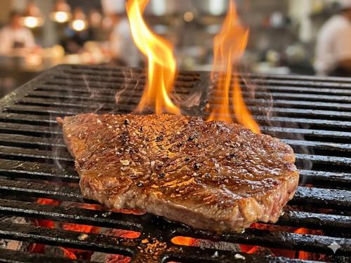 a piece of meat on a grill with flames at 森のうた Morinouta Forest Stay in Nikko in Nikko
