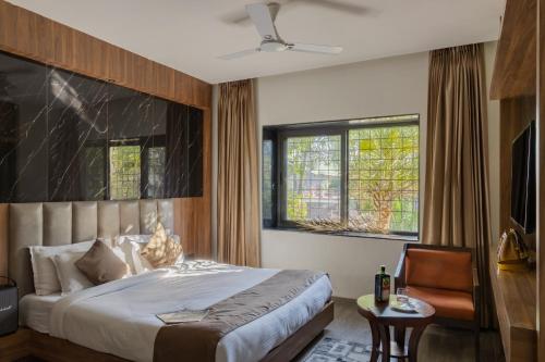 a bedroom with a bed and a chair and windows at Hotel Rock Regency Mount Abu - A Boutique Rodetel in Mount Ābu