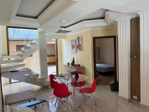 a living room with a table and red chairs at Chácara com Piscina in Poços de Caldas