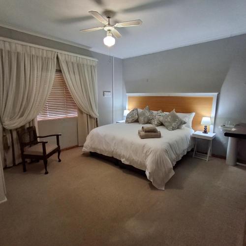 a bedroom with a large white bed with a ceiling fan at Vir Oulaas Guesthouse in Nieuwoudtville