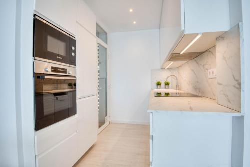 a kitchen with white cabinets and a sink and a stove at Seafront apartment in Platja d'Aro with parking in Platja d'Aro