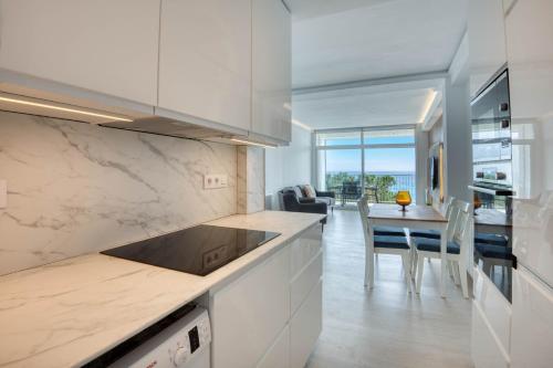 a kitchen with white cabinets and a dining room at Seafront apartment in Platja d'Aro with parking in Platja d'Aro