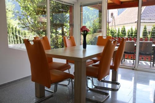 a dining room table with chairs and a vase with flowers at Apartment Alana in Podvelka