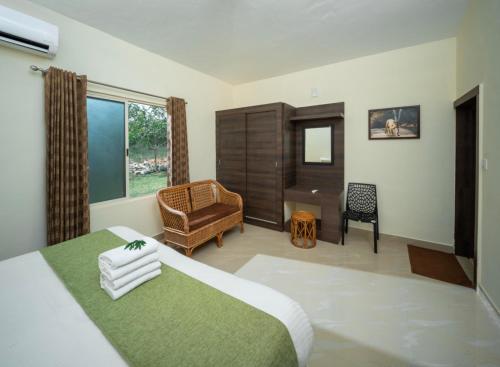 a bedroom with a bed and a chair and a desk at The Wild Forest Resorts in Masinagudi