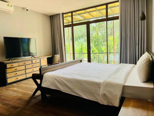 a bedroom with a large bed and a television at Lan Anh Villas Resort in Da Lat