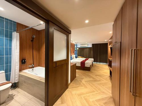 a bathroom with a bath tub and a bed in a room at Baywalk Residence Pattaya in Pattaya