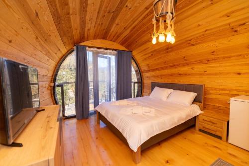a bedroom in a log cabin with a bed and a tv at Cottages Chateau Ochia in Koromkhet'i