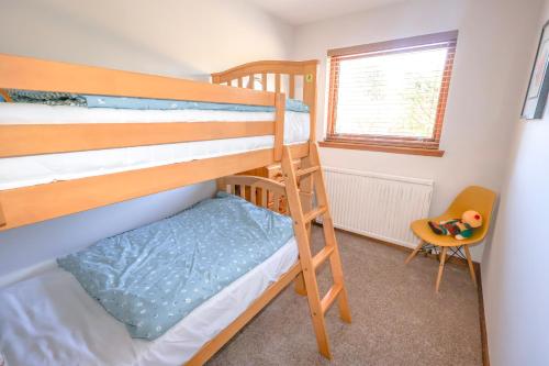 a bunk bed room with two bunk beds and a chair at Ardmara in Belladrum