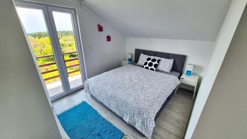 a bedroom with a bed and a large window at Le Petit in Čilipi