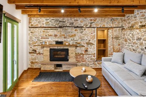 a living room with a stone fireplace and a couch at Casa Di Nonno-Jacuzzi Mountain View Stay in Lesvos in Agiásos