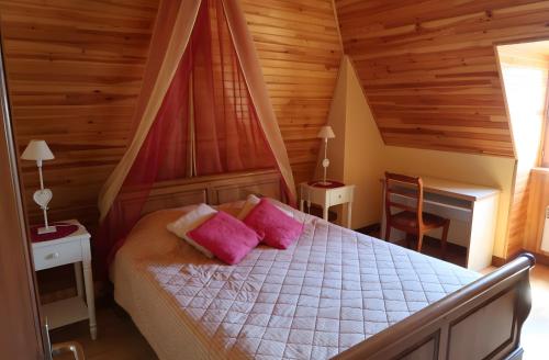 a bedroom with a bed with pink pillows and a desk at Gîte de Pradevin in Jou-sous-Monjou