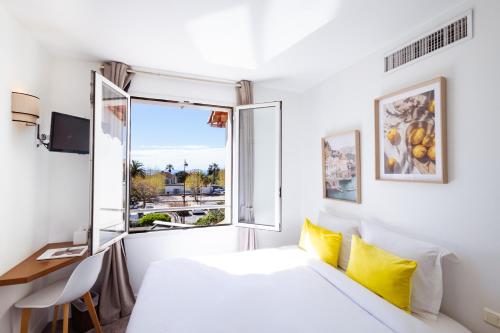 a white room with a bed and a window at Hôtel la Rotonde in La Croix-Valmer