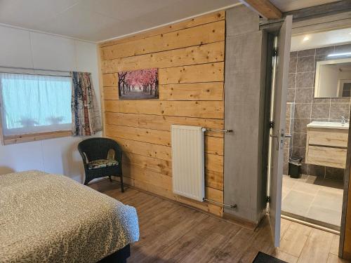 a bedroom with a wooden wall and a bed and a bathroom at Little Creek - Lodges in het natuurgebied in Renesse