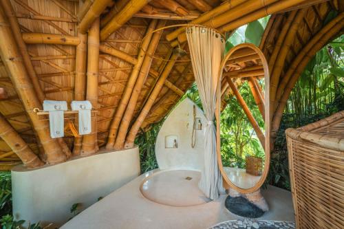 a bath tub in a room with a wooden ceiling at Green Earth Bali luxury Bamboo villas in Sidemen
