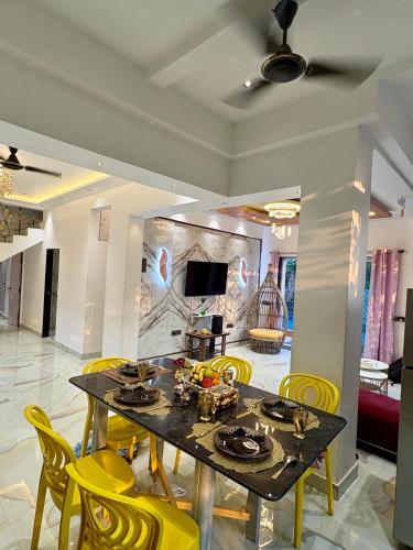 a dining room with a table and yellow chairs at Eko Nest Grand 5BHK Villa in Lonavala