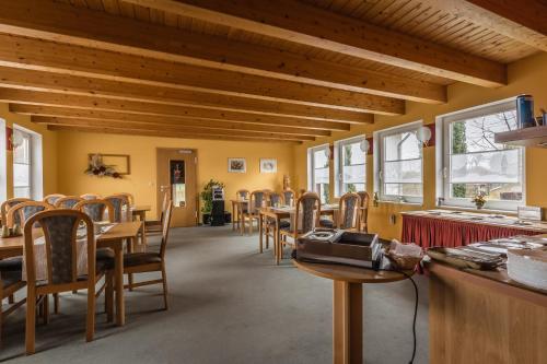 a dining room with tables and chairs and windows at Hotel-Pension am Rosarium in Sangerhausen