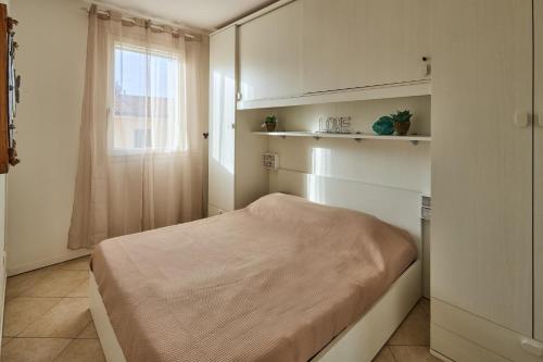 a small bedroom with a bed and a window at Badesi Sea Dunes in Codaruina