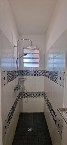 a bathroom with a shower with black and white tiles at Ti Ker Créole in Saint-Benoît