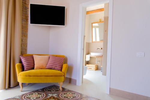ein Wohnzimmer mit einem gelben Sessel und einem Fernseher in der Unterkunft La Carrera in Bernalda