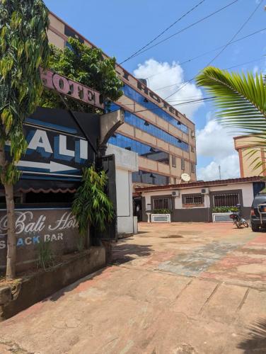 a building with a sign in front of a parking lot at BALI HOTEl in Yaoundé