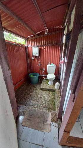 a bathroom with a toilet in a red wall at Sada 360 Nanu Homestay in Sembalun Lawang