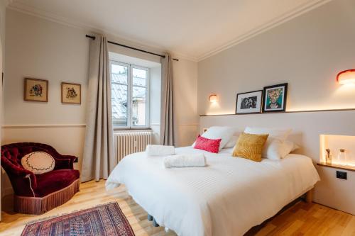 a bedroom with a large white bed and a chair at Le Falcoz in Saint-Jean-de-Maurienne