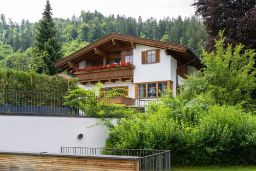 a house with a balcony with red flowers on it at Villa Schwarzbrunn in Stans